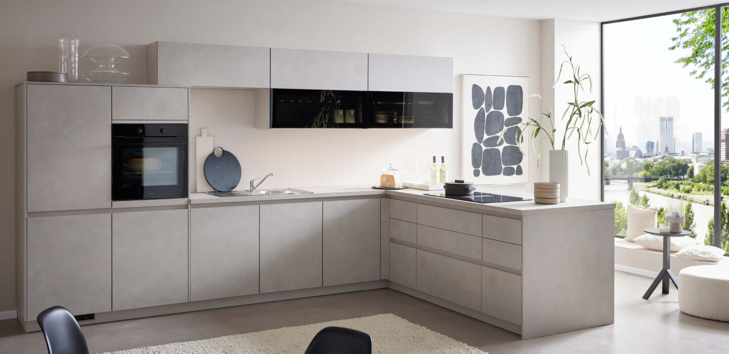 Moderne L-Küche in Betonoptik mit klaren Linien, integrierten Geräten und großer Fensterfront mit Stadtblick, kombiniert mit minimalistischer Dekoration und hellen Farbtönen